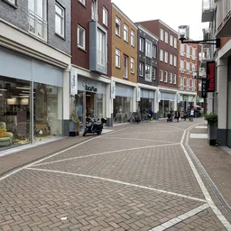 Winkelstraat met winkelpuien en voetgangers, fietsen geparkeerd voor een winkel