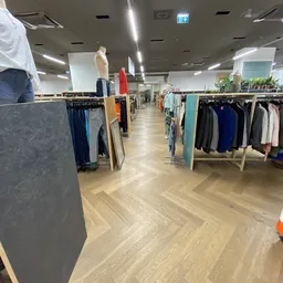 Winkelvloer met kledingrekken en mannequins in kringloopwinkel