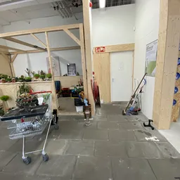 Winkelvloer met stellingen, planten, gereedschap en diverse spullen in een kringloopwinkel