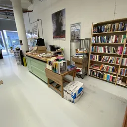 Winkelvloer met boekenkasten, groen bureau en diverse meubels en spullen uitgestald