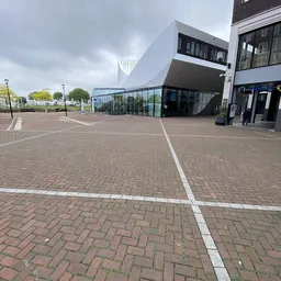 Exterieur van moderne kringloopwinkel met bakstenen plein en glazen ingang