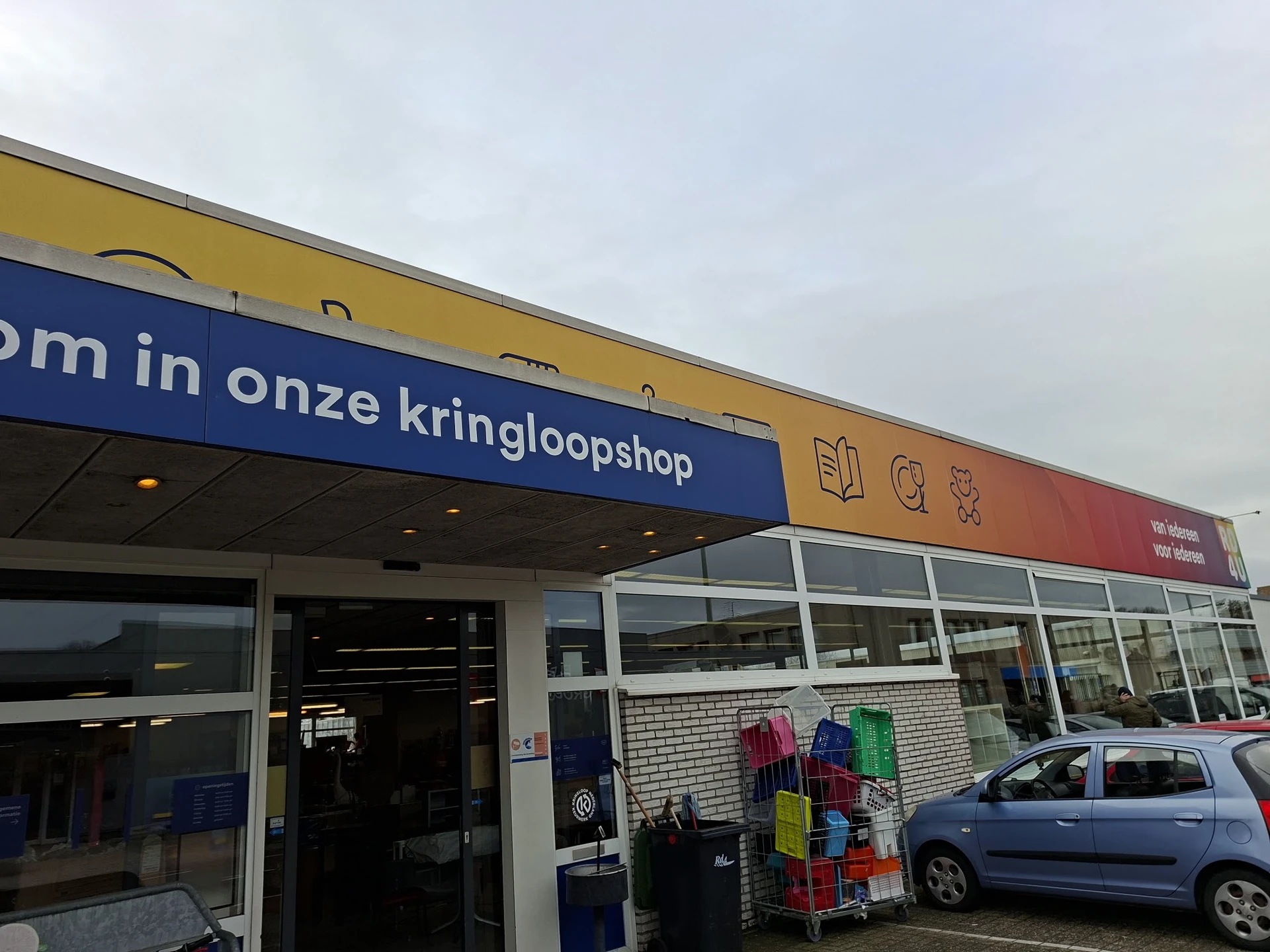 Gevel van RD4U kringloopshop met blauwe en gele luifel, winkelramen en ingang met uithangbord