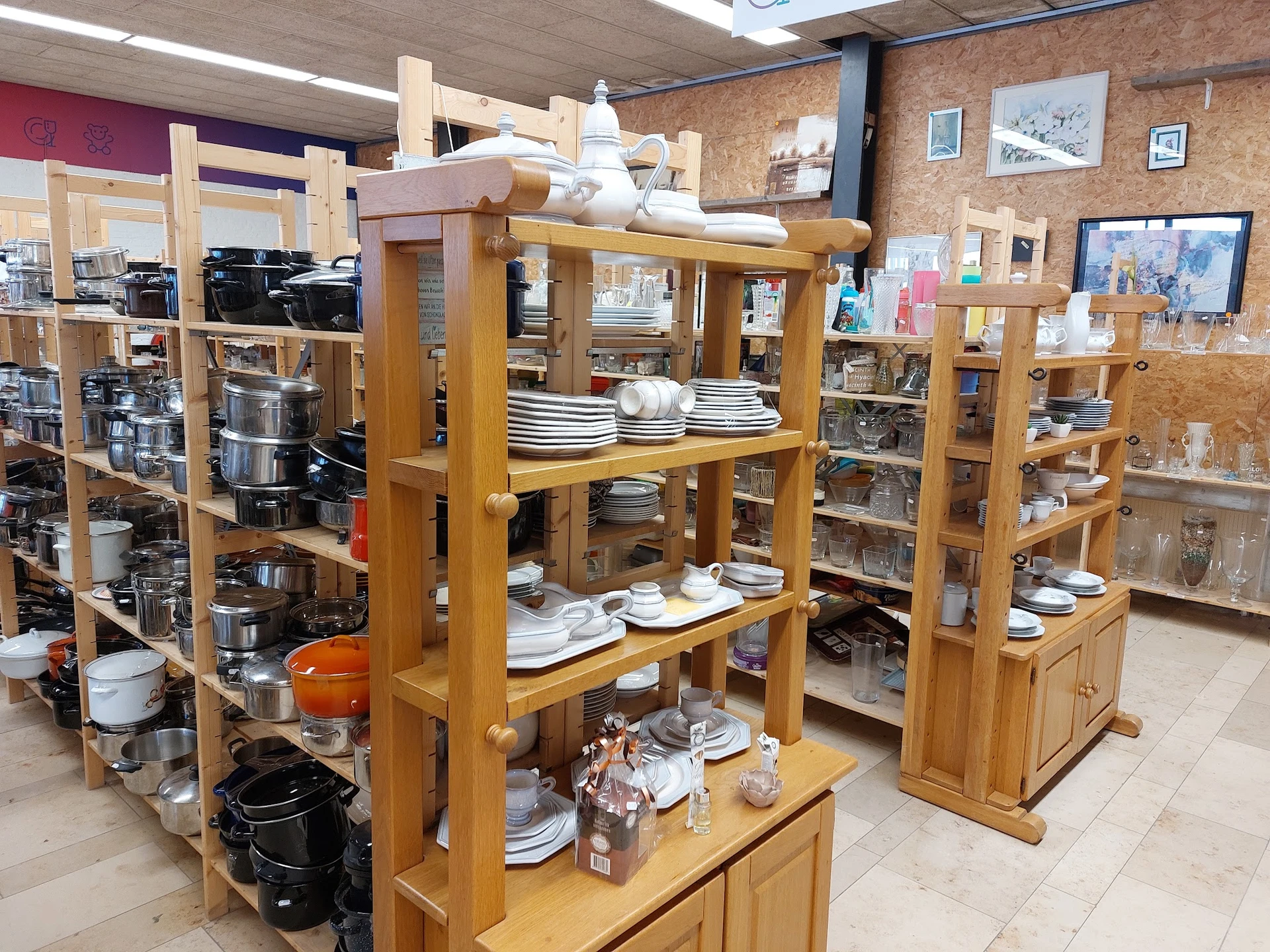 Houten stellingen met servies, borden en keukengerei in kringloopwinkel