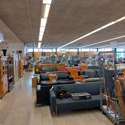 Winkelvloer met zwartleren banken en gele kussens, stellingen met artikelen op de achtergrond