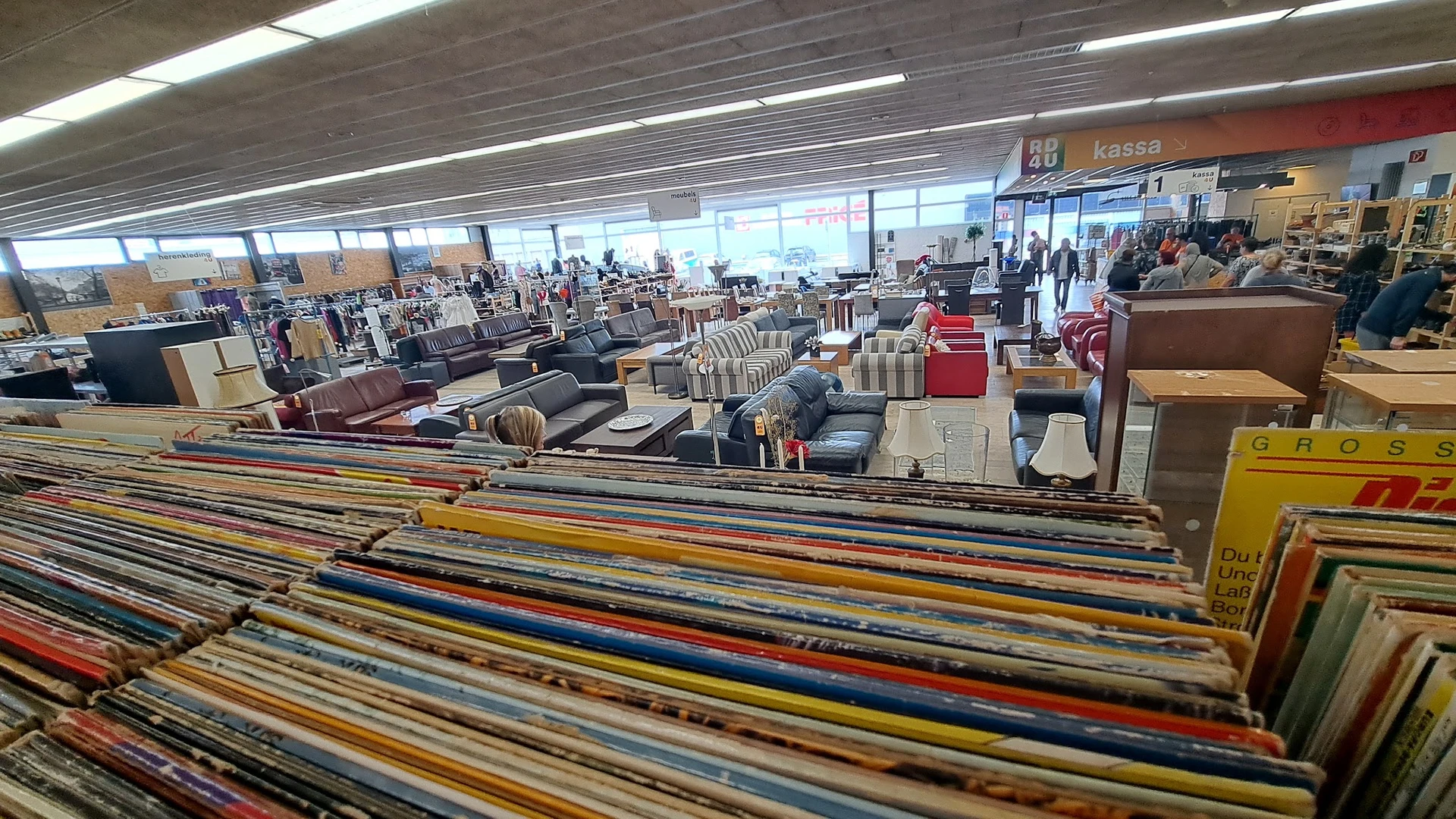 Stellingen met kleurrijke tweedehands meubels en huishoudartikelen in de kringloopwinkel