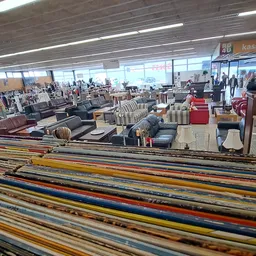 Stellingen met kleurrijke tweedehands meubels en huishoudartikelen in de kringloopwinkel