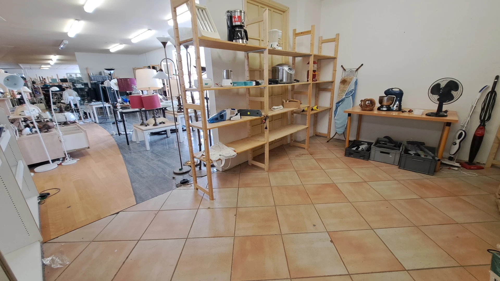 Winkelvloer met houten stellingen en uitgestalde spullen in een kringloopwinkel