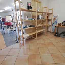 Winkelvloer met houten stellingen en uitgestalde spullen in een kringloopwinkel
