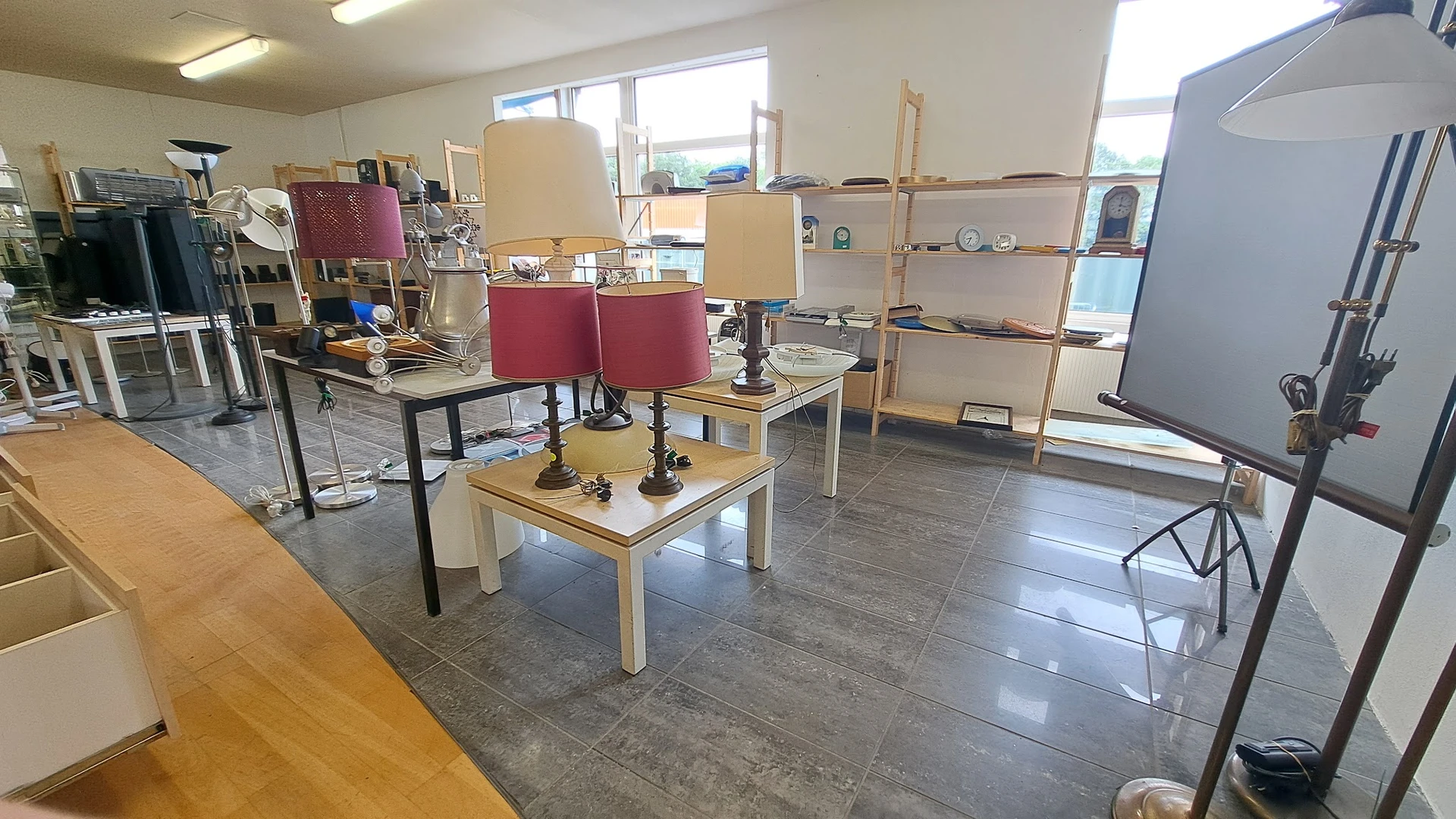 Winkelvloer met houten tafels, rode stoelen, houten stellingen en diverse winkelspreiding
