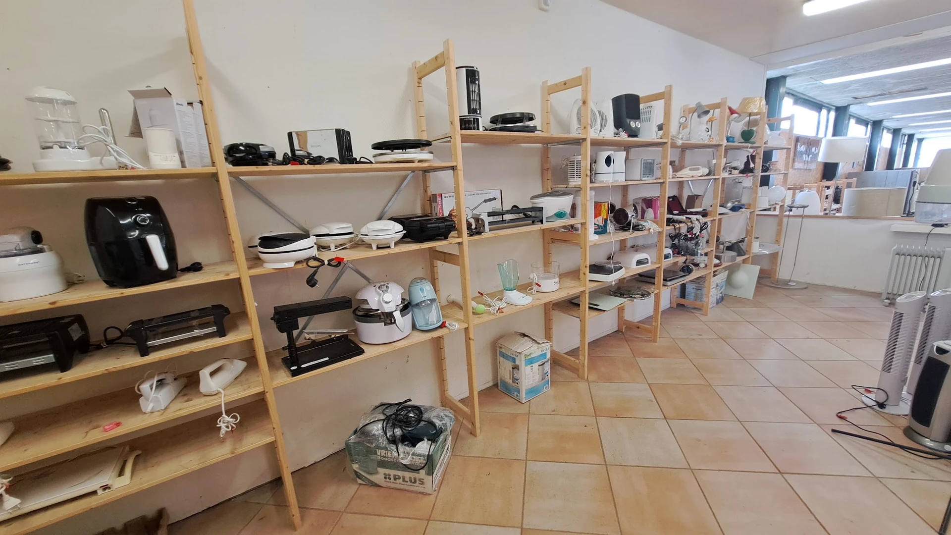 Houten stellingen met huishoudelijke artikelen, keukenapparatuur en diverse spullen in een kringloopwinkel