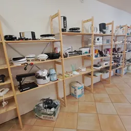 Houten stellingen met huishoudelijke artikelen, keukenapparatuur en diverse spullen in een kringloopwinkel