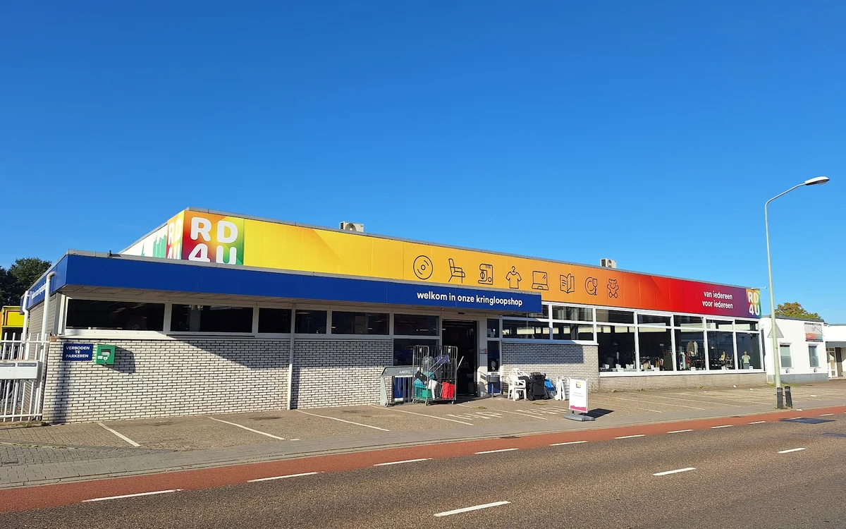 Gevel van RD4U kringloopshop met geel en blauw/rood kleurig uithangbord aan de Cramer in Heerlen