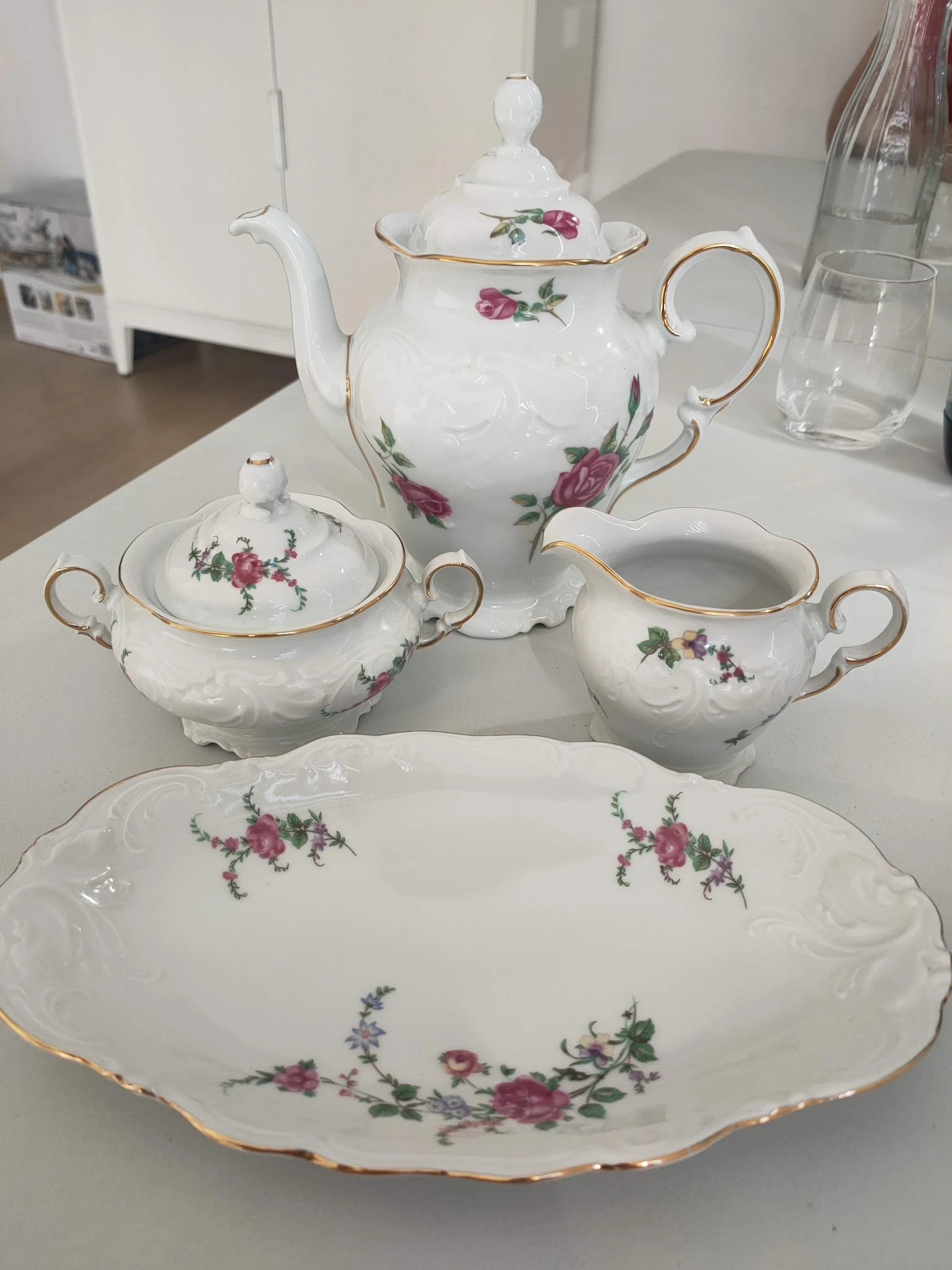 Wit porseleinservies met roze bloemenpatroon: theepot, suikerpot, melkkan en bord