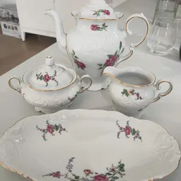 Wit porseleinservies met roze bloemenpatroon: theepot, suikerpot, melkkan en bord