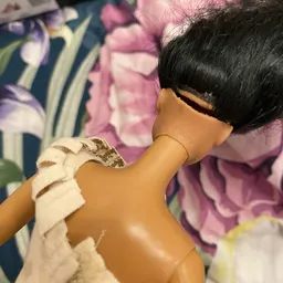 Close-up van een pop of mannequin met zwart haar en wit kledingstuk
