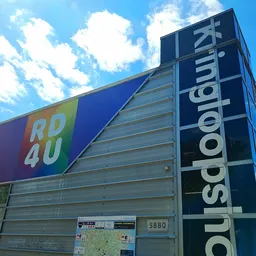 Voorkant van kringloopwinkel met blauwe luifel en winkelnaam 'RD4U' en 'IsodoNaum' op de zijkant