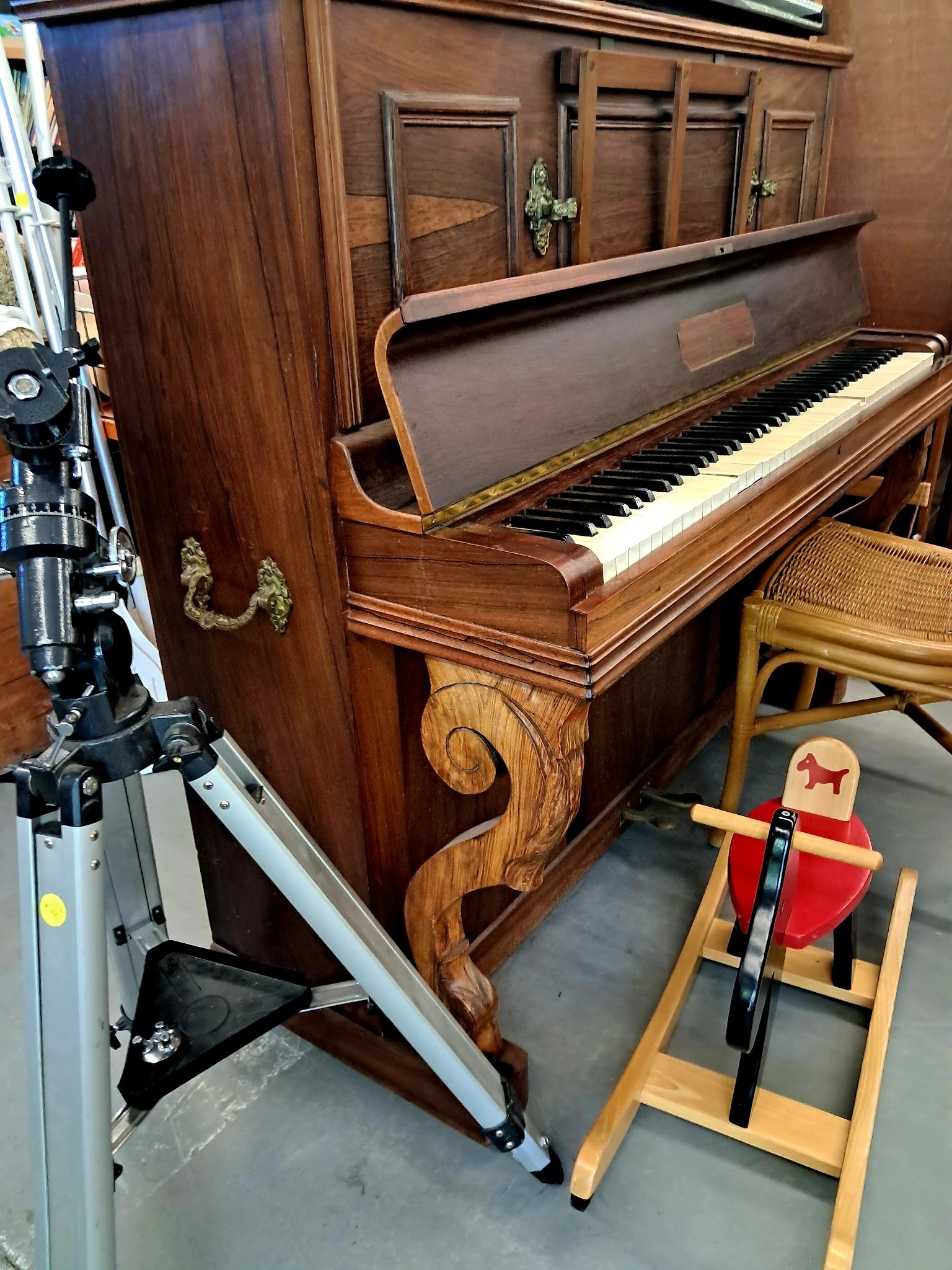 Houten vleugelpiano in bruine kleur met zichtbaar toetsenbord en ornamentale details aan de zijkant
