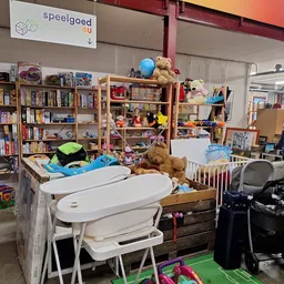 Winkelvloer met stellingen vol boeken, speelgoed, kindermeubels en huishoudartikelen in een kringloopwinkel