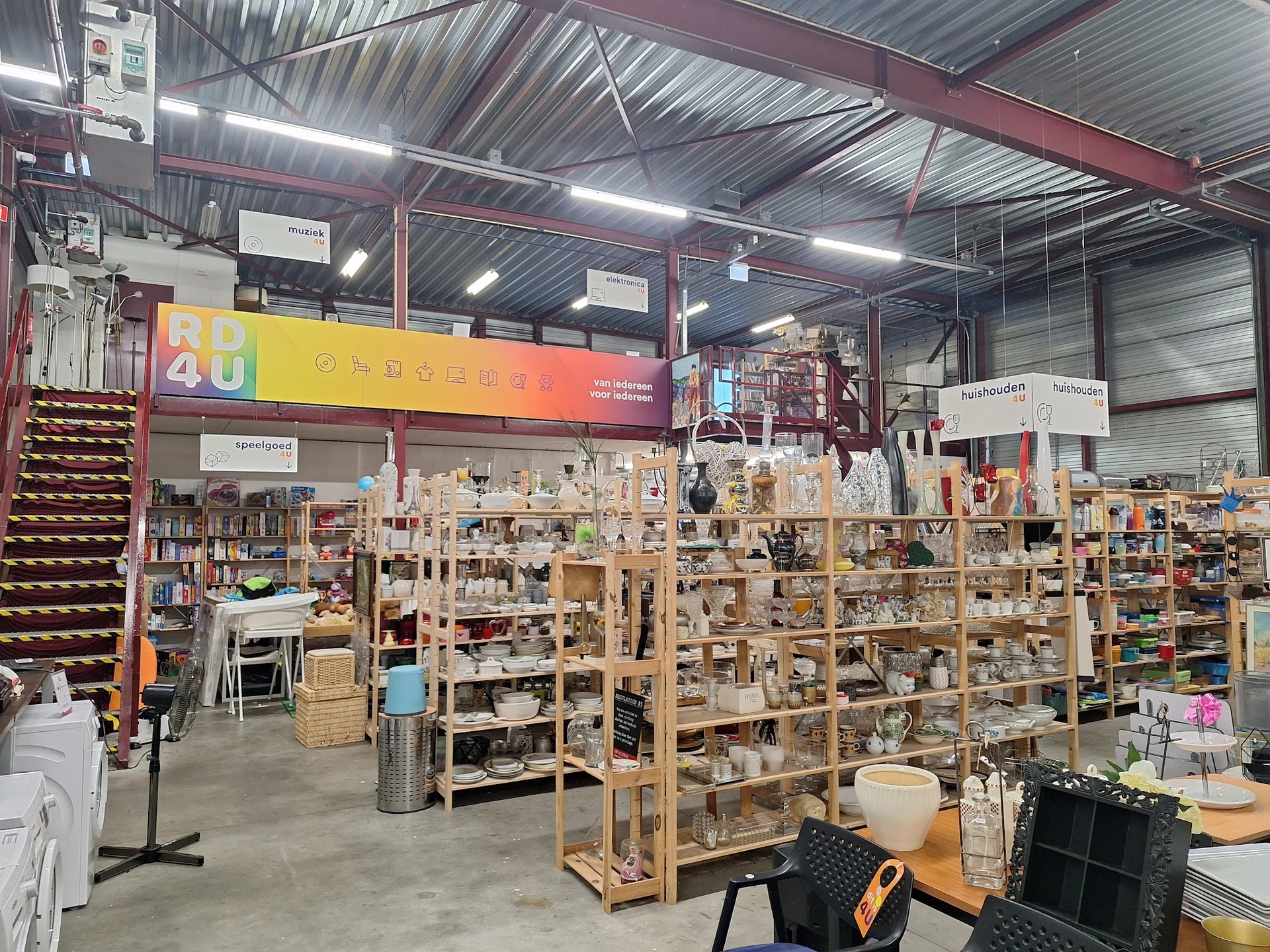 Winkelvloer met houten stellingen vol diverse tweedehands spullen en huishoudartikelen