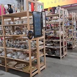 Houten stellingen met huishoudelijke artikelen, servies en decoratiespullen in de kringloopwinkel