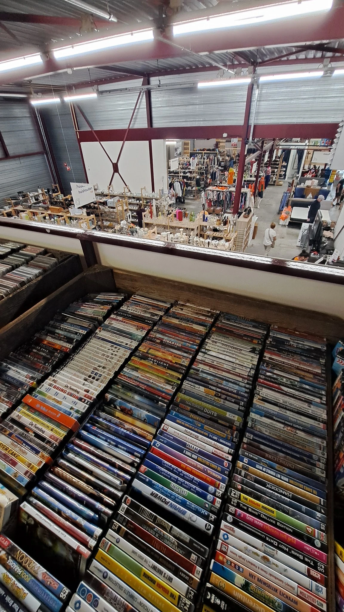 Uitgestalde cd's en dvd's in bakken, gerangschikt per genre in een kringloopwinkel