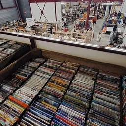 Uitgestalde cd's en dvd's in bakken, gerangschikt per genre in een kringloopwinkel
