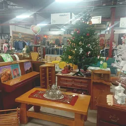 Winkelvloer met houten meubels, kerstboom, kledingrekken en diverse spullen in kringloopwinkel