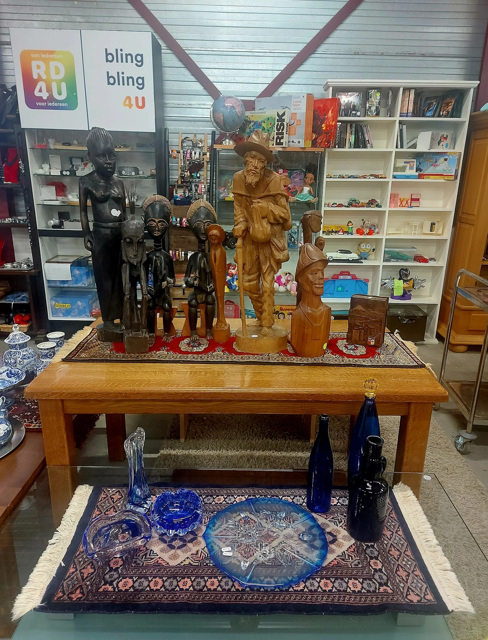 Houten beelden en standbeelden op een tafel in de winkel, waaronder figuren van verschillende grootte en uitvoering