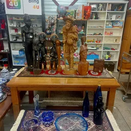 Houten beelden en standbeelden op een tafel in de winkel, waaronder figuren van verschillende grootte en uitvoering