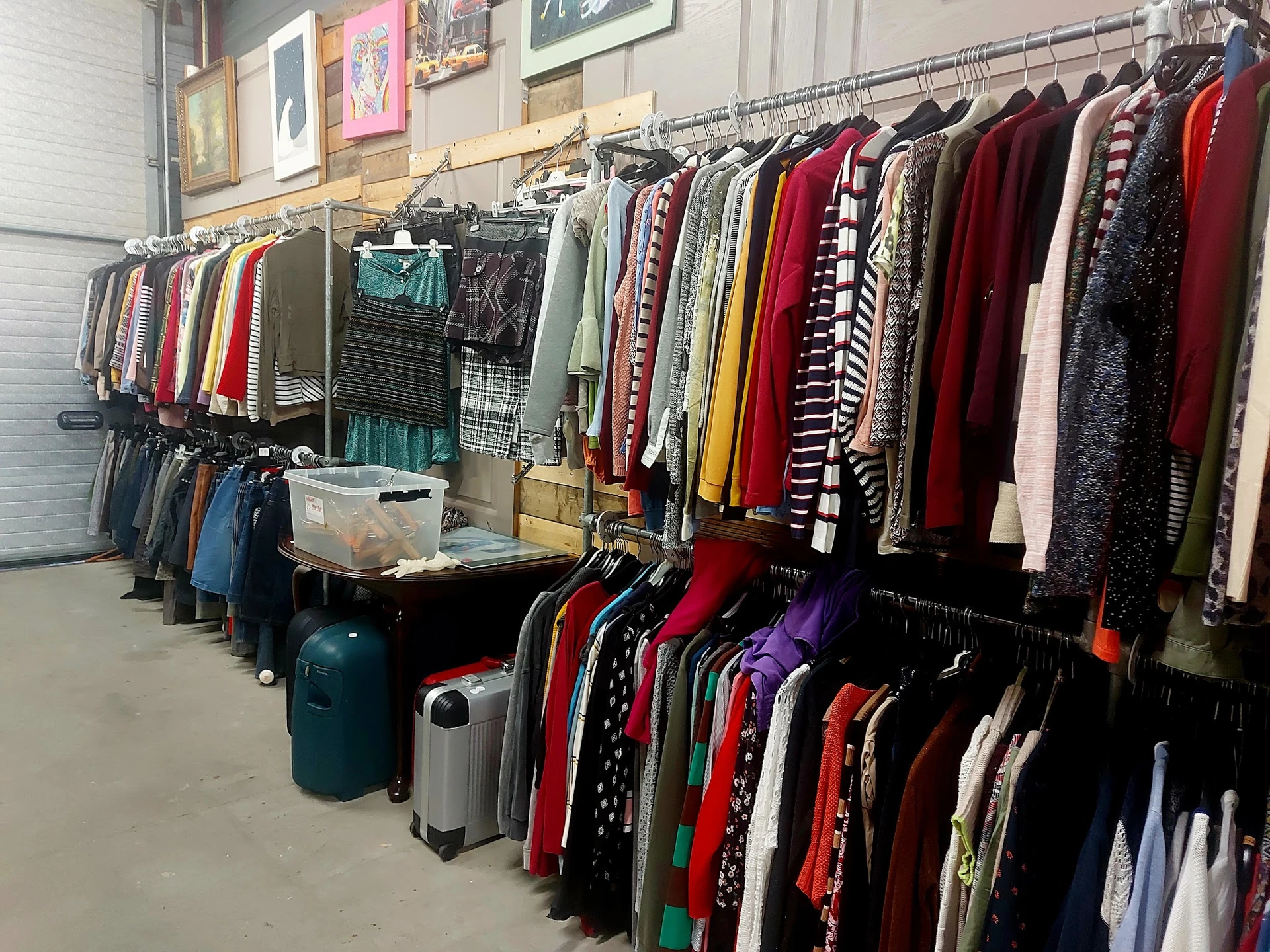 Rekken met tweedehands kleding, jassen en truien in verschillende kleuren georganiseerd in de winkel