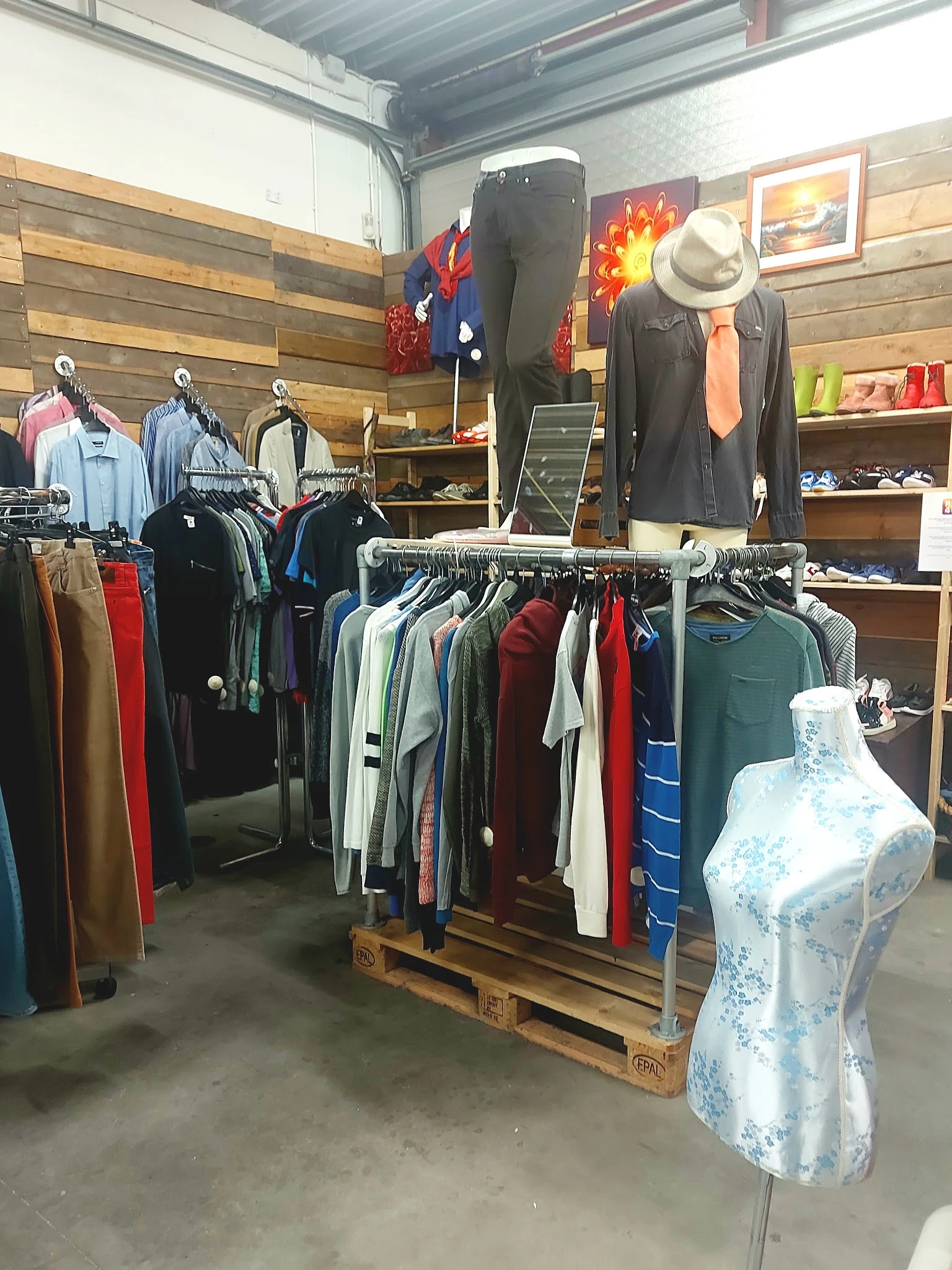 Rekken met tweedehands kleding in diverse kleuren en stijlen, inclusief jassen, broeken en shirts