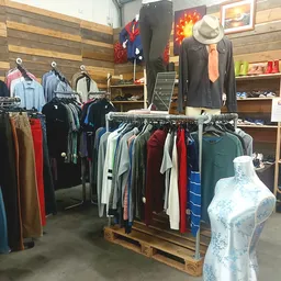 Rekken met tweedehands kleding in diverse kleuren en stijlen, inclusief jassen, broeken en shirts