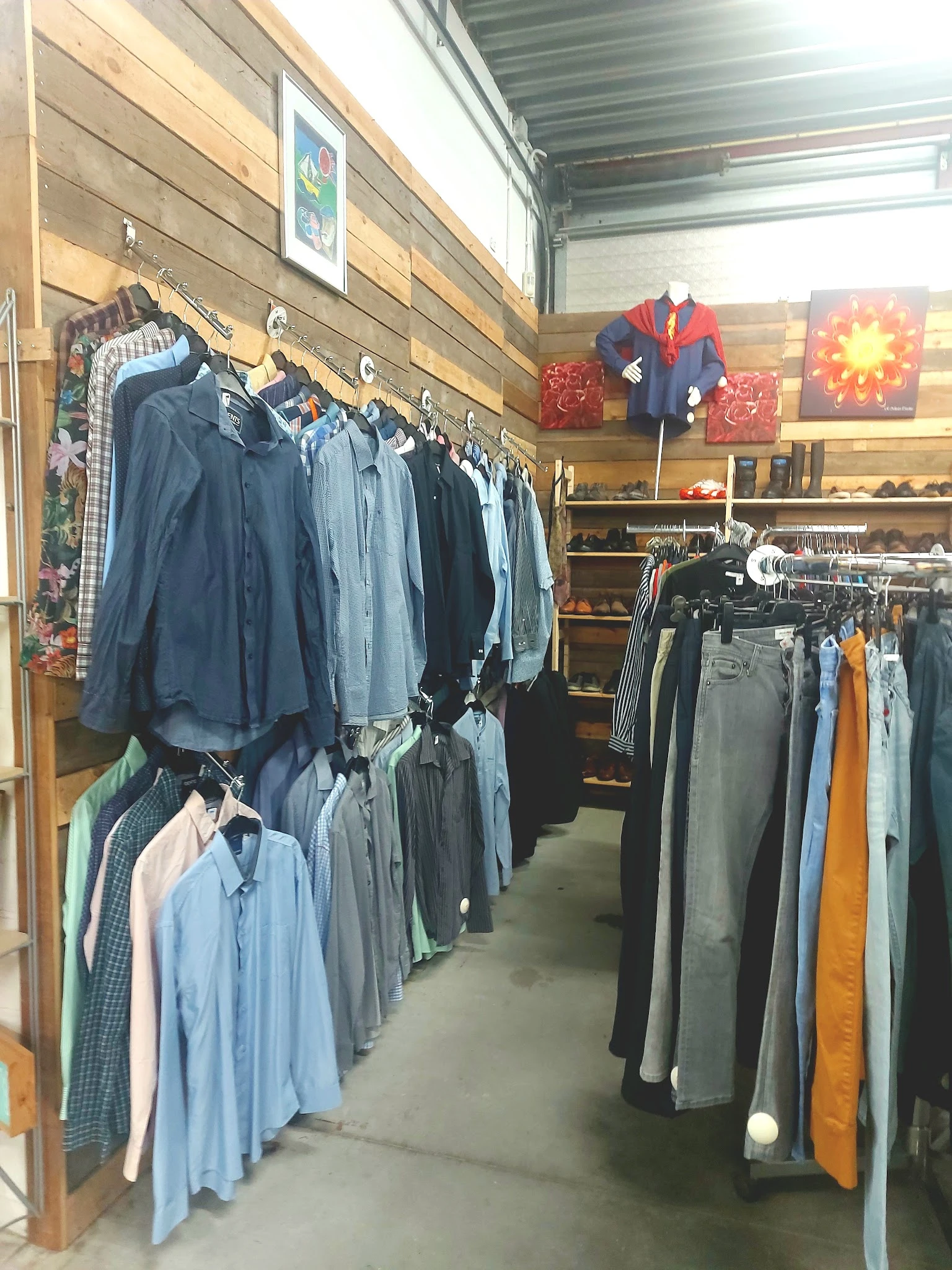 Rekken met tweedehands herenkledij, onder meer jassen en shirts in blauwe tinten