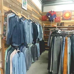 Rekken met tweedehands herenkledij, onder meer jassen en shirts in blauwe tinten