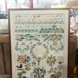 Ingelijste cross-stitch of borduurwerk met alfabetten, nummers, bloemmotieven en decoratieve patronen