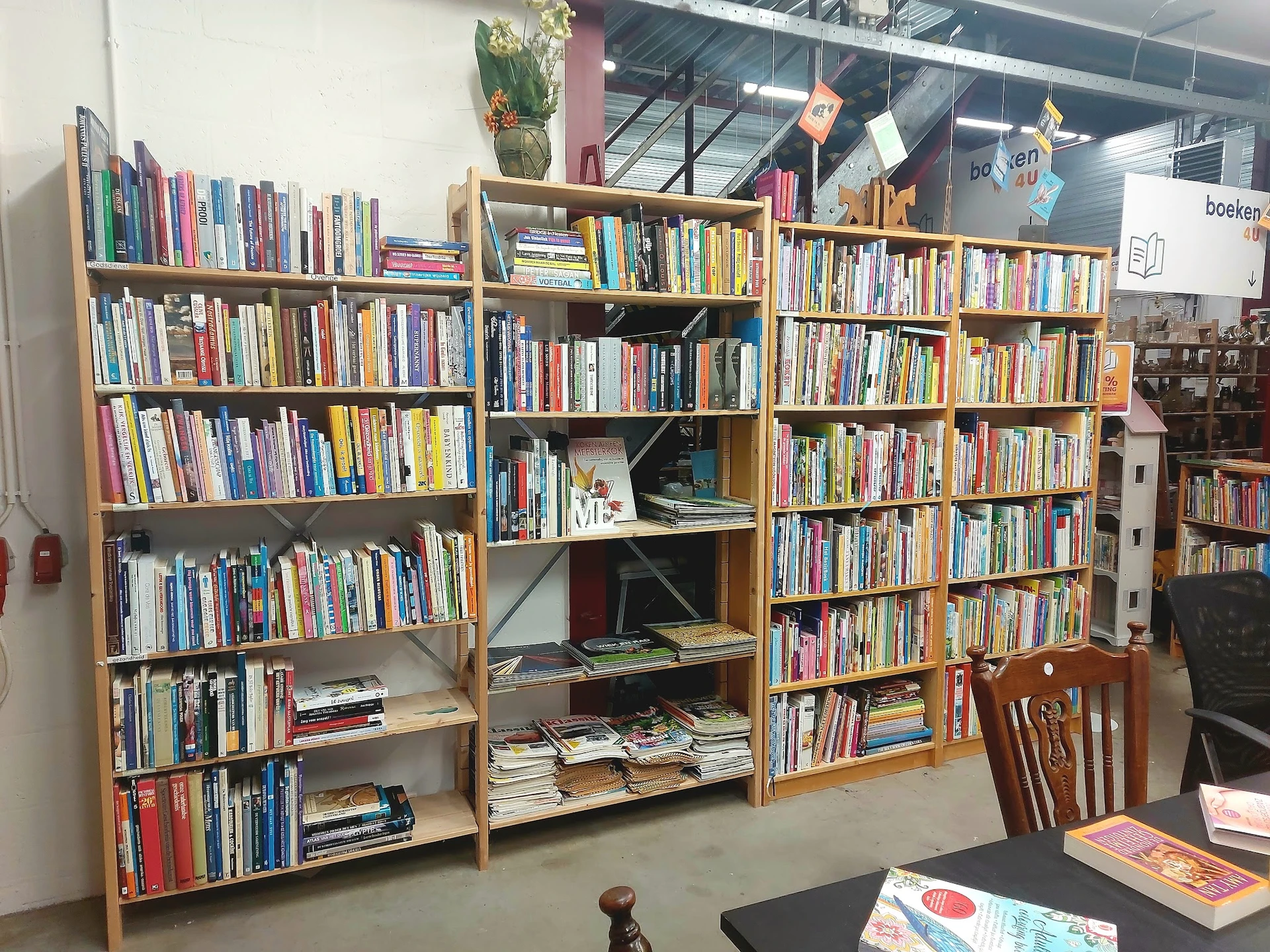 Houten boekenkasten tegen de wand gevuld met tweedehands boeken in een kringloopwinkel