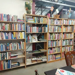 Houten boekenkasten tegen de wand gevuld met tweedehands boeken in een kringloopwinkel