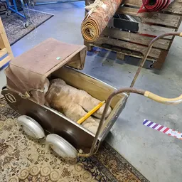 Vintage kinderwagen met bruine stof en gele metalen frame op wielen