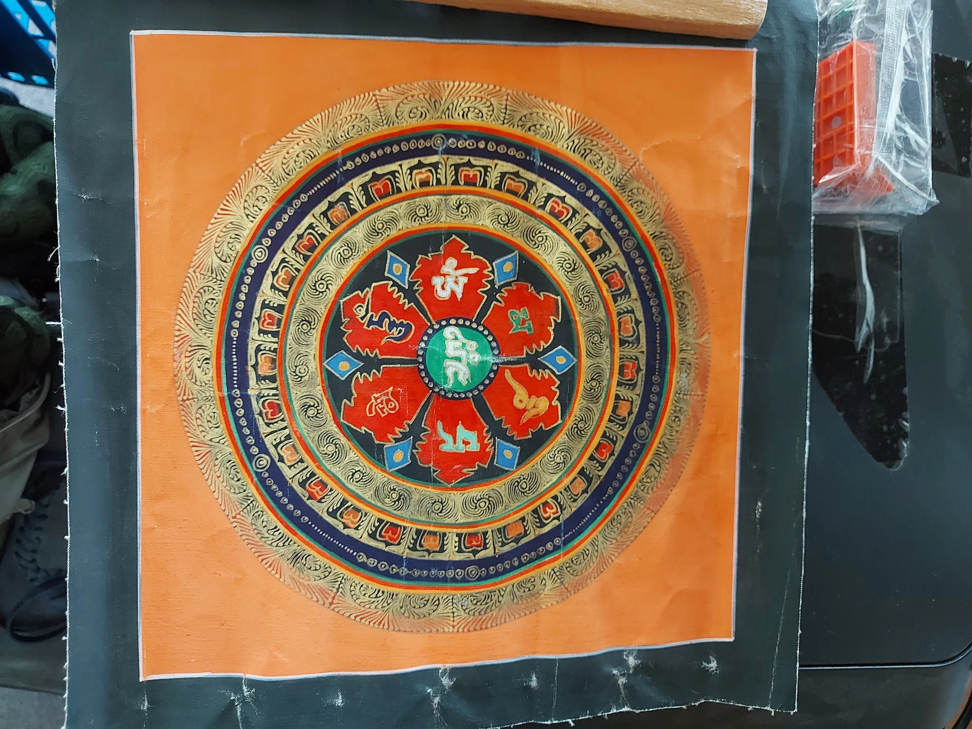 Decoratief mandala-kunstwerk met oranje achtergrond en rood bloemmotief in het centrum