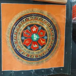 Decoratief mandala-kunstwerk met oranje achtergrond en rood bloemmotief in het centrum