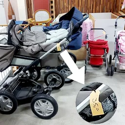 Diverse tweedehands kinderwagens en buggy's uitgestald in de winkel, waaronder modellen in zwart, blauw, roze en rood