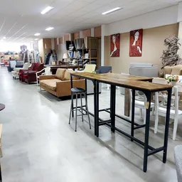 Winkelvloer met diverse meubels: barkruk bij houten bartafel, bruine fauteuils, decoratieve objecten en kasten op stellingen
