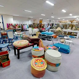 Ruim interieur van kringloopwinkel met diverse meubels, stoelen, trommels en huishoudelijke artikelen