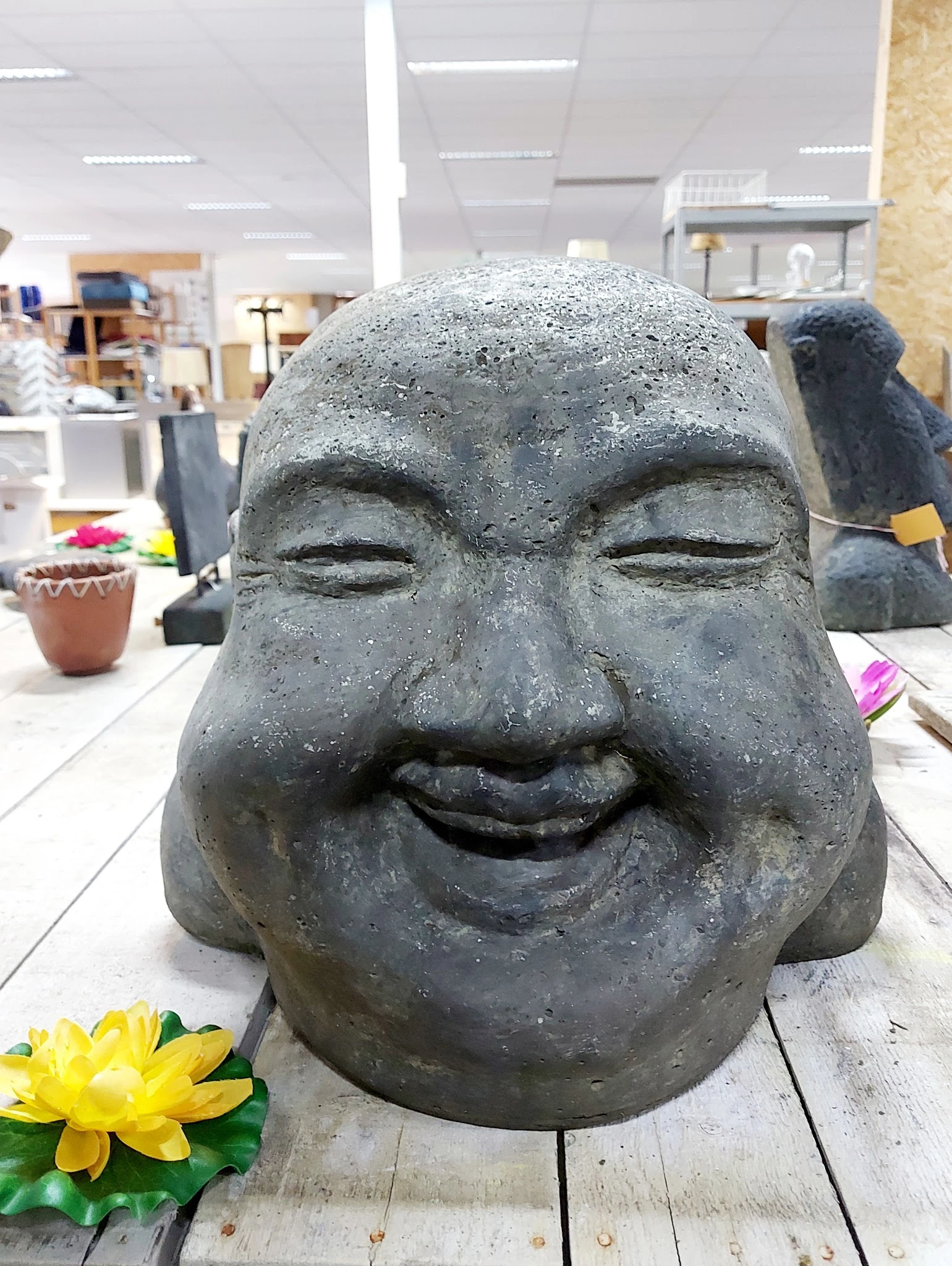 Stenen beeldhouwwerk van een lachend gezicht in close-up, tentoongesteld in de winkel