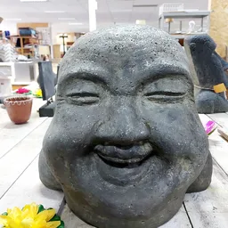 Stenen beeldhouwwerk van een lachend gezicht in close-up, tentoongesteld in de winkel