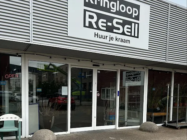 Gevel van kringloopwinkel Re-Sell met witte pui, glazen deuren en winkelnaam op bord