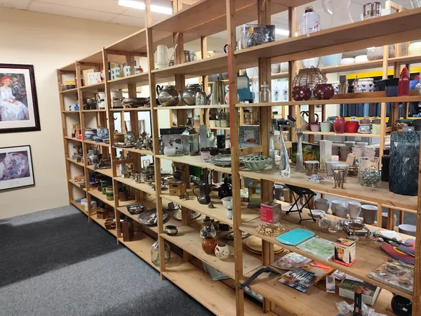 Houten stellingen met diverse tweedehands artikelen, decoratie en huishoudspullen in kringloopwinkel