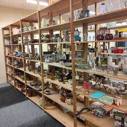 Houten stellingen met diverse tweedehands artikelen, decoratie en huishoudspullen in kringloopwinkel