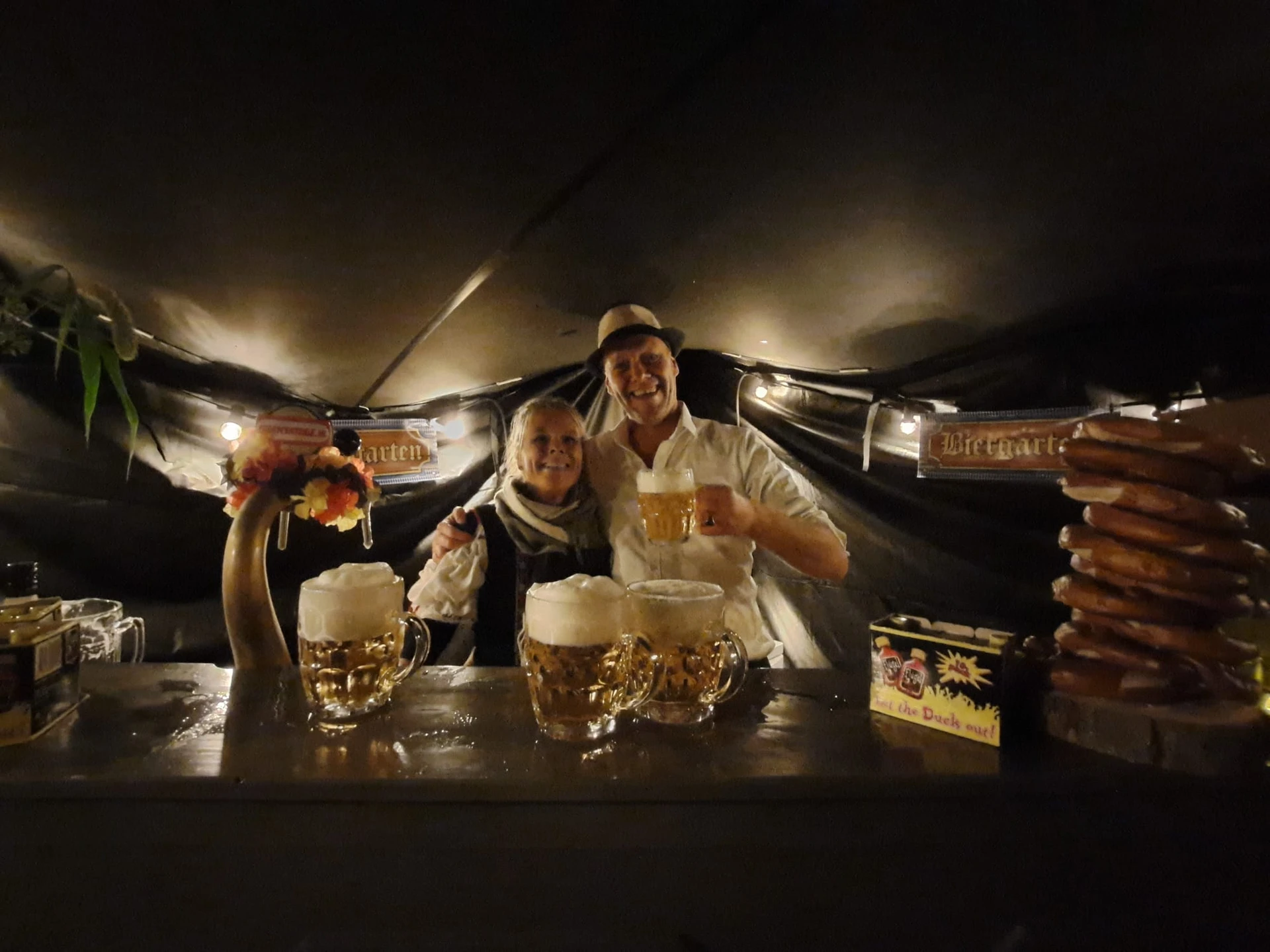 Twee mannen in Tiroler kledij achter een toog met biertappen en gevulde bierglazen