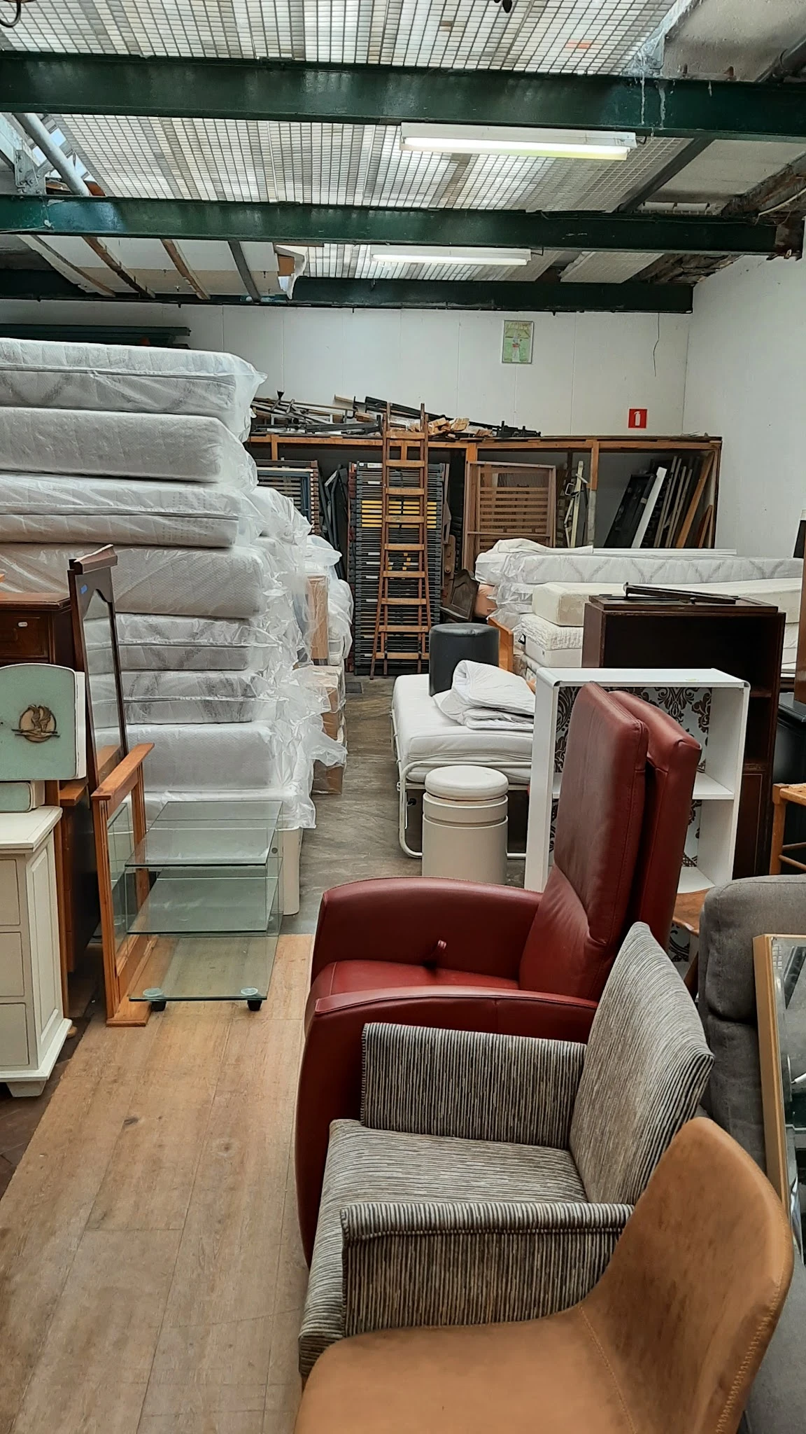 Uitgestalde tweedehandsmeubels in de winkel: matrassen, stoelen, kasten en andere meubelstukken